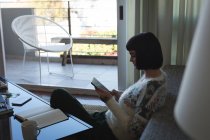 Женщина, использующая цифровой планшет в гостиной дома — стоковое фото