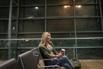 Mulher tomando café na área de espera no aeroporto — Fotografia de Stock