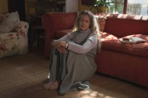 Nachdenkliche reife Frau sitzt zu Hause auf dem Boden — Stockfoto