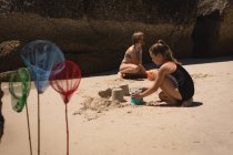 Братья и сестры играют на песке на пляже в солнечный день — стоковое фото