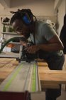 Madera niveladora de carpintero con máquina pulidora en taller - foto de stock