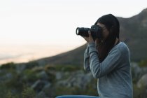 Donna cliccando foto con una fotocamera al crepuscolo — Foto stock