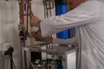 Operaio di sesso maschile che esamina gin nel cilindro di misura in fabbrica — Foto stock