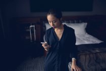 Mujer usando el teléfono móvil en la habitación de hotel - foto de stock