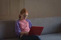 Chica usando el ordenador portátil en la sala de estar en casa - foto de stock