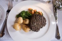 Close-up de bife de carne servida em prato com prato lateral na mesa — Fotografia de Stock