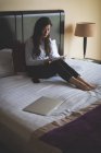 Mujer de negocios usando tableta digital en la cama en la habitación de hotel - foto de stock