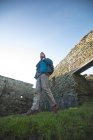Junger männlicher Wanderer, der in alten Ruinen auf dem Land wandert, Blick aus dem niedrigen Winkel — Stockfoto