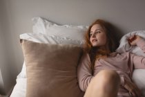 Mulher atenciosa relaxando na cama no quarto em casa — Fotografia de Stock