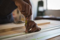 Mid section of carpenter nailing in metal frame in workshop — Stock Photo