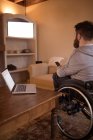 Hombre discapacitado viendo televisión en la sala de estar en casa - foto de stock