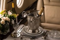 Champagnerflasche mit Glas auf einem Tisch im Privatjet — Stockfoto