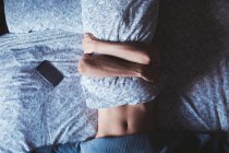 Женщина обнимает подушку, пока спит в спальне дома — стоковое фото