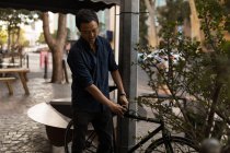 Uomo d'affari che blocca la bicicletta sul palo nel caffè della pavimentazione — Foto stock