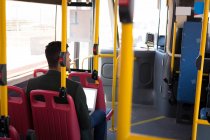 Visão traseira do empresário usando laptop enquanto viaja em ônibus — Fotografia de Stock
