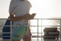 Media sezione di donna che utilizza il telefono cellulare sulla nave da crociera — Foto stock