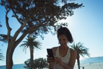 Bella donna matura che prende selfie con il telefono cellulare sulla costa tropicale — Foto stock
