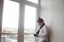 Женщина держит цифровую камеру возле окна дома . — стоковое фото