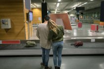 Вид сзади на пару, обнимающую друг друга в аэропорту — стоковое фото