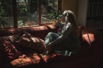 Зріла жінка розслабляється на дивані у вітальні вдома — стокове фото