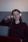 Молода жінка слухає музику зі своїм ноутбуком у вітальні — стокове фото