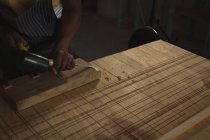 Sección media del carpintero tallando madera en la mesa en el taller - foto de stock