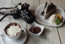 Крупный план камеры и вкусная сладкая еда на деревянном столе — стоковое фото