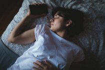 Mulher com telefone celular dormindo no quarto em casa — Fotografia de Stock