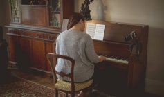 Задний вид женщины-блогера, играющей на пианино дома — стоковое фото