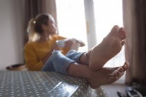 Thoughtful woman with feet up having coffee at home — Stock Photo