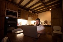 Disabled young man using laptop at home — Stock Photo