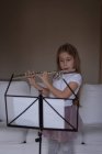 Ragazza che suona il flauto in soggiorno a casa — Foto stock