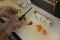 Крупный план шеф-повара, готовящего суши на кухне в ресторане — стоковое фото