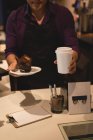 Офіціант, який подає каву і кекс у тарілці в кав'ярні — стокове фото