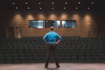 Male actor standing with hands on hips on stage at theatre. — Stock Photo