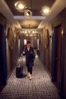 Mulher com saco de carrinho andando no corredor do hotel — Fotografia de Stock