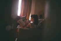 Жінка читає книгу у вітальні вдома — стокове фото
