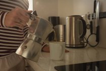 Donna versando il caffè in tazza in cucina a casa — Foto stock