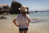 Rückansicht eines Mädchens, das mit den Händen an der Hüfte am Strand steht — Stockfoto