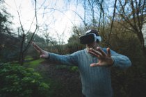 Человек использует гарнитуру виртуальной реальности в лесу в сельской местности — стоковое фото
