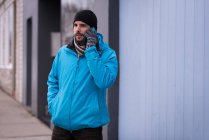 Мужчина разговаривает по мобильному телефону на городской улице зимой . — стоковое фото