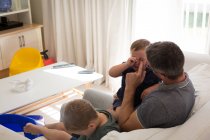 Батько з синами відпочиває у вітальні вдома — стокове фото