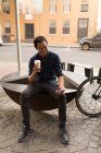Empresário usando telefone celular enquanto toma café no café do pavimento — Fotografia de Stock