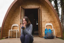 Beautiful woman having coffee outside the log cabin — Stock Photo
