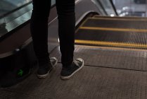 Baixa seção de mulher de pé perto escada rolante na estação — Fotografia de Stock