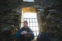 Joven excursionista masculino usando mapa en ruinas antiguas - foto de stock