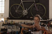 Jeune femme mécanicien fixation vélo dans l'atelier — Photo de stock
