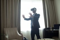 Homem de negócios usando headset realidade virtual no quarto de hotel — Fotografia de Stock