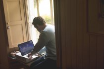 Hombre atento usando el ordenador portátil en casa - foto de stock