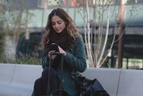 Junge Frau benutzt Handy an einem sonnigen Tag — Stockfoto
